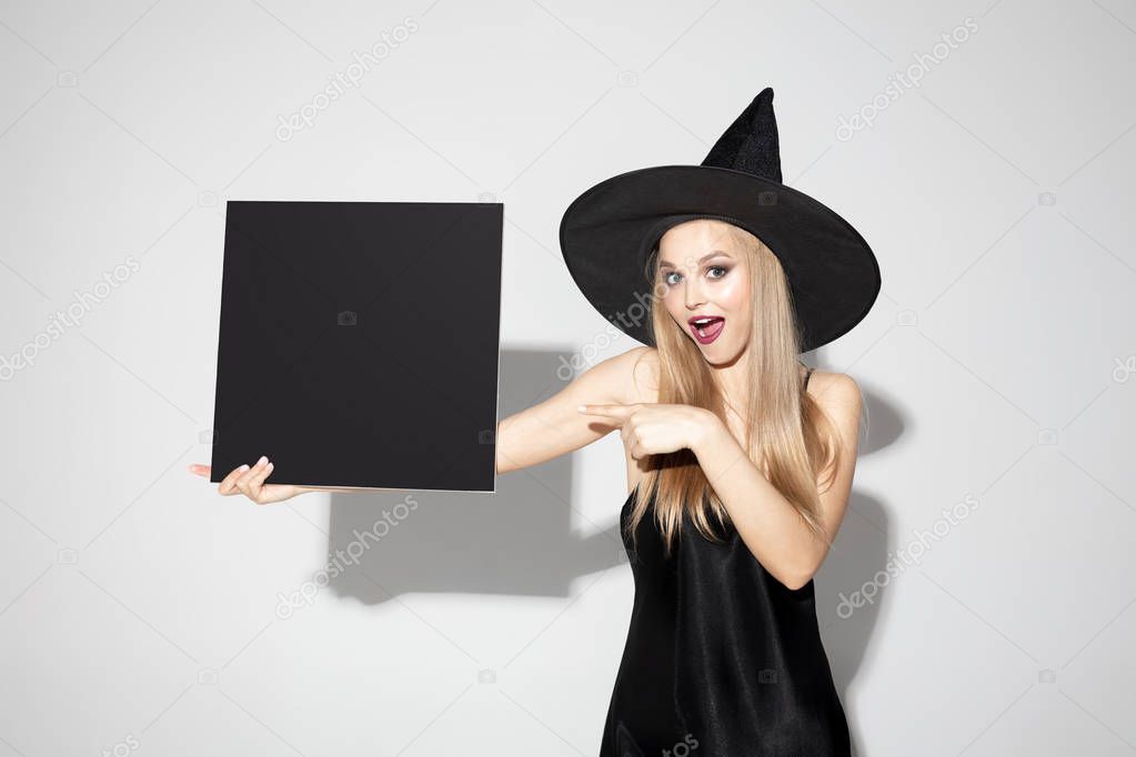 Young woman in hat as a witch on white background