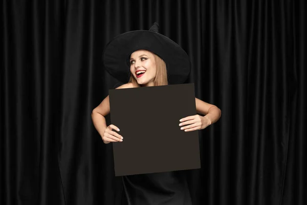 Ung kvinna i hatt som en häxa på svart bakgrund — Stockfoto