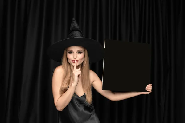 Giovane donna in cappello come una strega su sfondo nero — Foto Stock