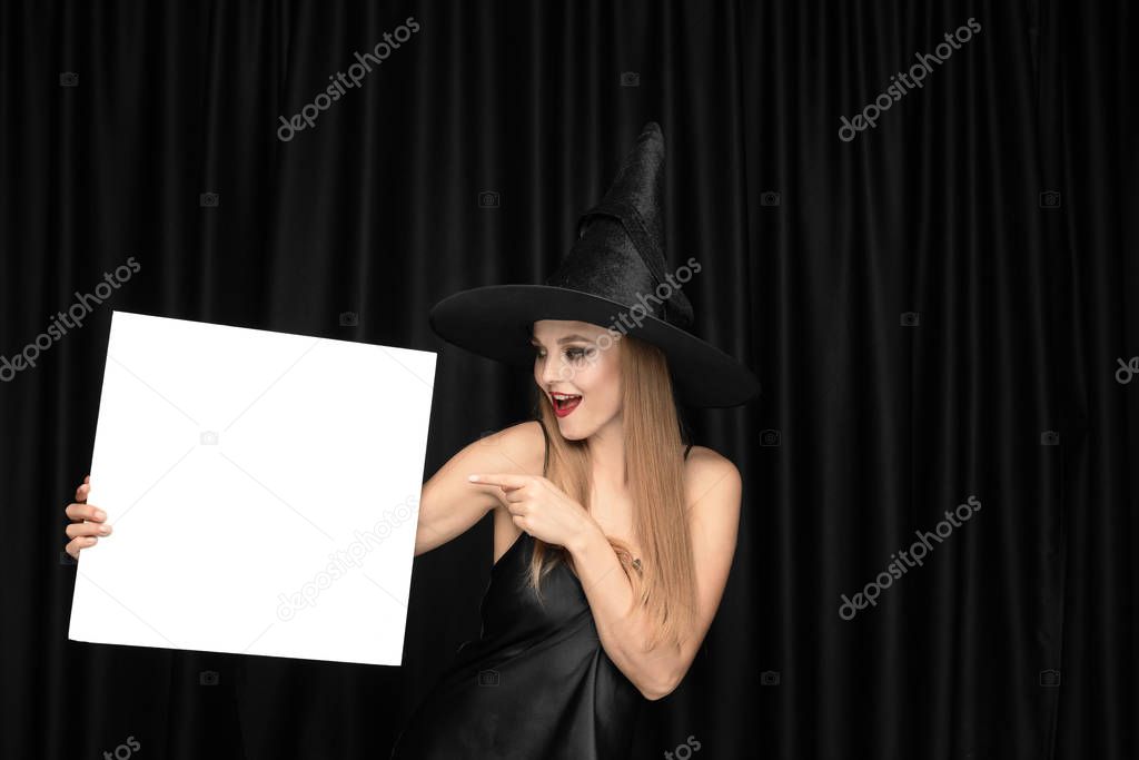 Young woman in hat as a witch on black background
