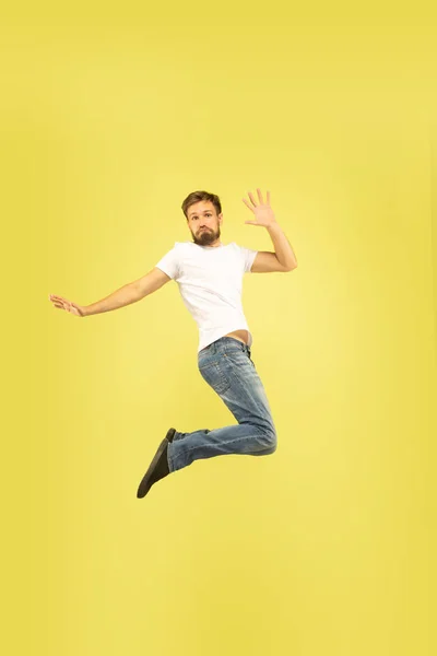 Täyspitkä muotokuva onnellinen hyppäävä mies keltaisella pohjalla — kuvapankkivalokuva