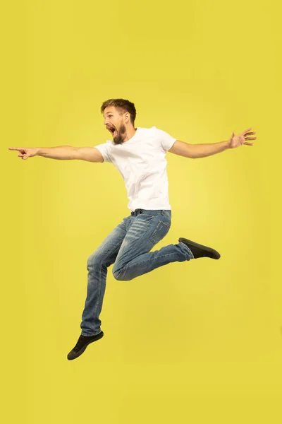 Täyspitkä muotokuva onnellinen hyppäävä mies keltaisella pohjalla — kuvapankkivalokuva