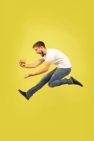 Full length portrait of happy jumping man on yellow background — Stock Photo, Image