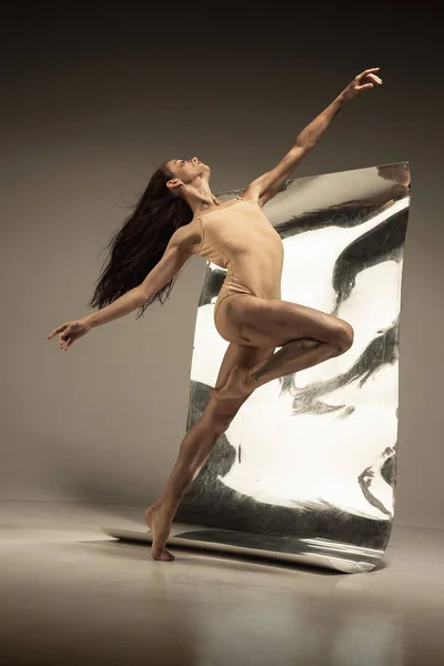 Jovem e elegante moderno bailarino de balé no fundo marrom — Fotografia de Stock