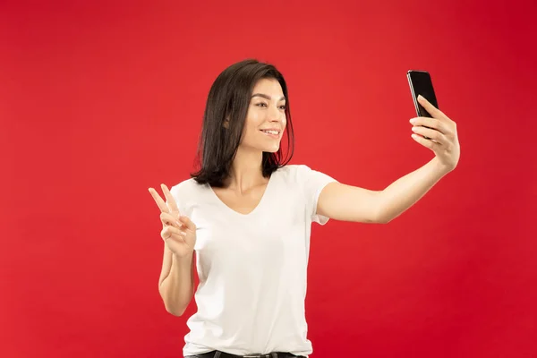 Caucasian young womans half-length portrait on red background — Stock Photo, Image