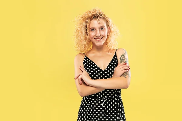 Caucasian young womans half-length portrait on yellow background