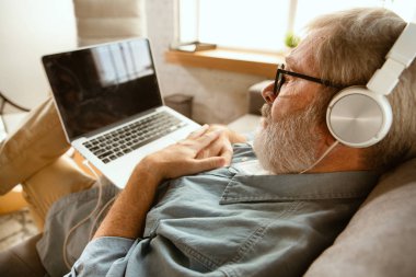 Evde dizüstü bilgisayar ile çalışan Kıdemli adam - ev eğitimi kavramı