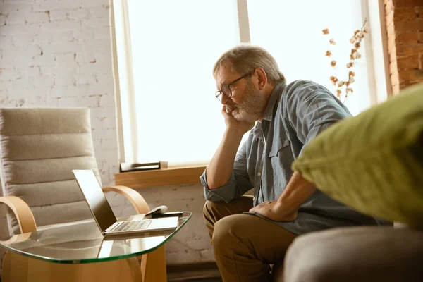 Senior man working with laptop at home - concept of home studying