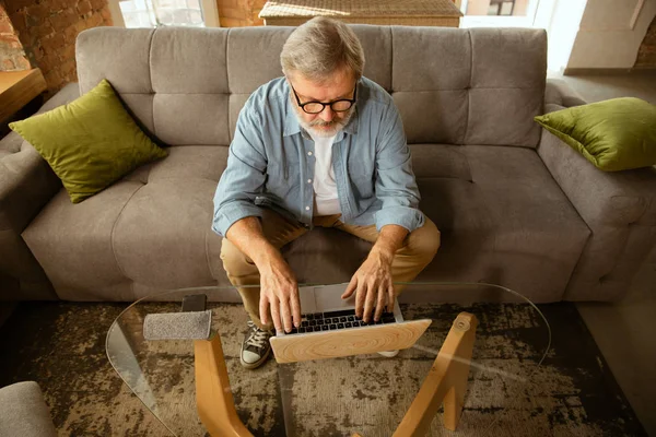 Старший чоловік, який працює з ноутбуком вдома концепція домашнього навчання — стокове фото