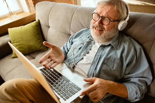Старший чоловік, який працює з ноутбуком вдома концепція домашнього навчання — стокове фото