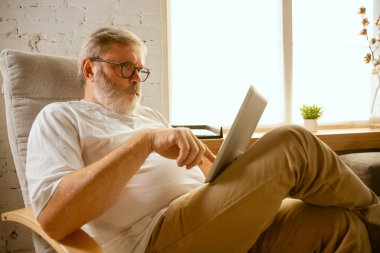 Evde tablet ile çalışan kıdemli adam - ev eğitimi kavramı