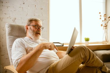 Evde tablet ile çalışan kıdemli adam - ev eğitimi kavramı