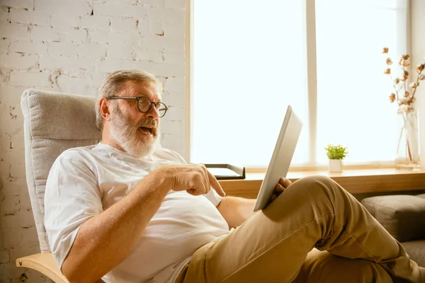 Старший чоловік, який працює з планшетом вдома концепція домашнього навчання — стокове фото