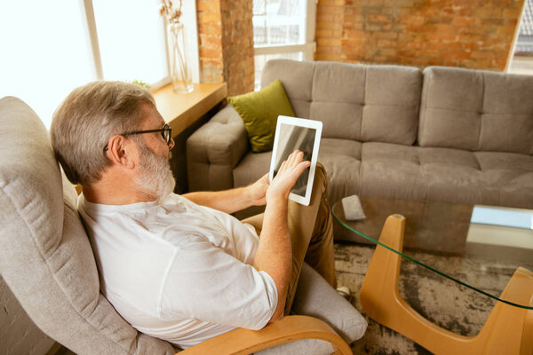 Senior man working with tablet at home - concept of home studying