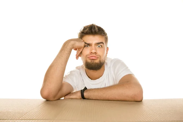 Young man opening the biggest postal package isolated on white — Stock Photo, Image