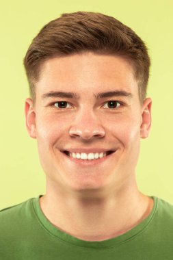 Beyaz genç adam yeşil arka planda çekim yakın