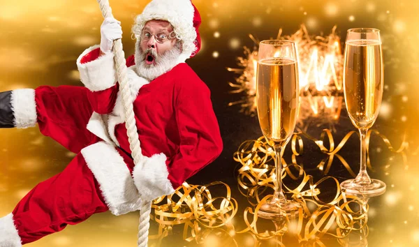 Happy Christmas Święty Mikołaj wspinaczka na liny z kieliszków szampana w tle — Zdjęcie stockowe