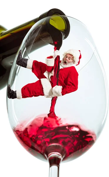 Happy Christmas Santa Claus climbing on trickle of wine on white background — Stock Photo, Image