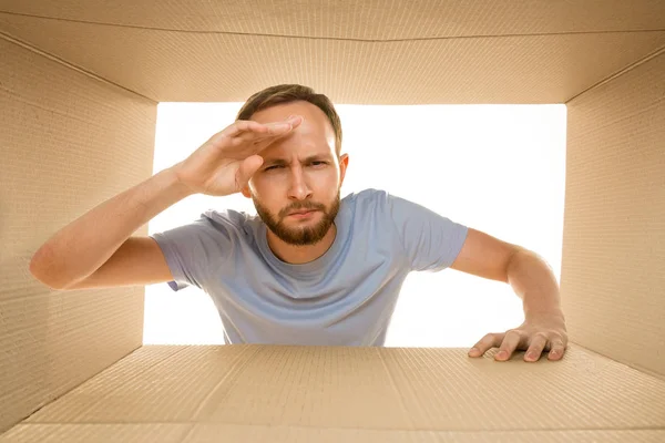 Giovane uomo che apre il più grande pacchetto postale isolato su bianco — Foto Stock