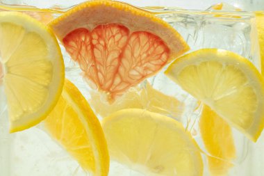 Arka planda limon ve greyfurt dilimlerinin limonata görünümünü kapat.
