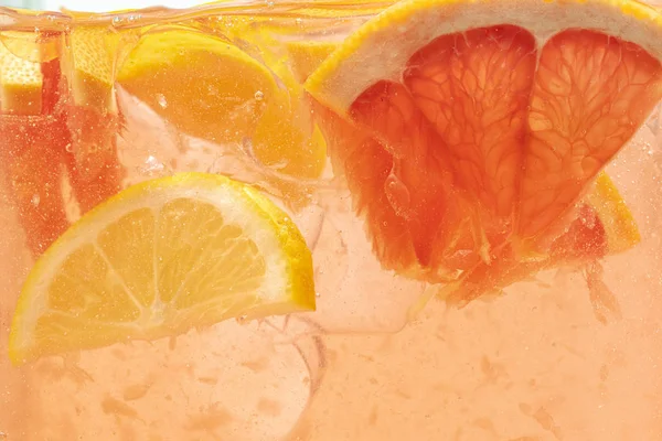 Vista de cerca de las rodajas de limón y pomelo en limonada sobre fondo —  Fotos de Stock