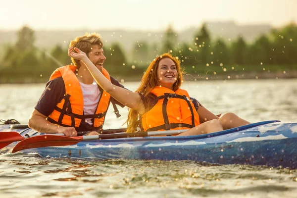 Coppia felice kayak sul fiume con tramonto sullo sfondo — Foto Stock