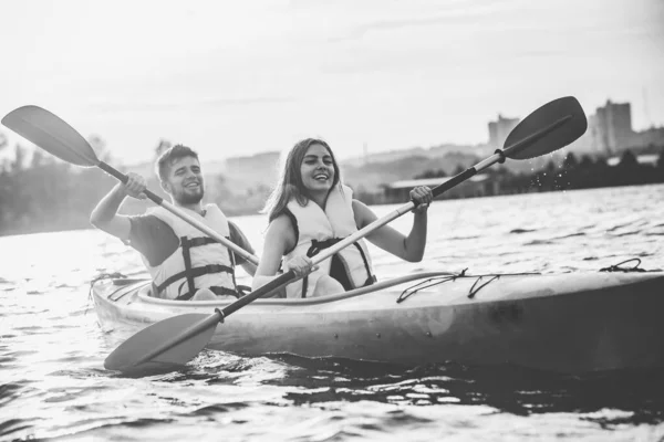 Happy couple kayaking on river with sunset on the background — Stock Photo, Image