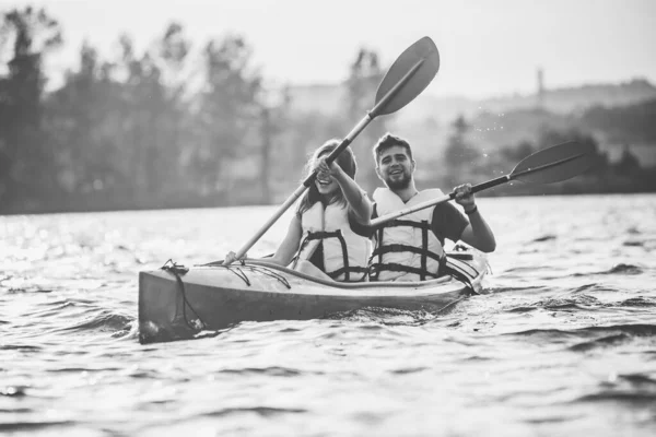 Happy couple kayaking on river with sunset on the background — Stock Photo, Image