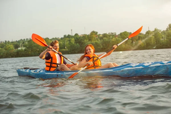 Happy couple kayaking on river with sunset on the background — Stock Photo, Image