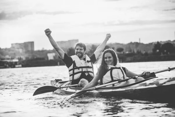 Happy couple kayaking on river with sunset on the background — Stock Photo, Image