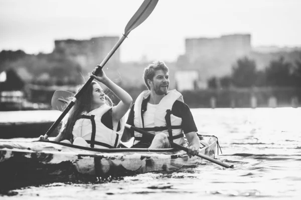 Happy couple kayaking on river with sunset on the background — Stock Photo, Image