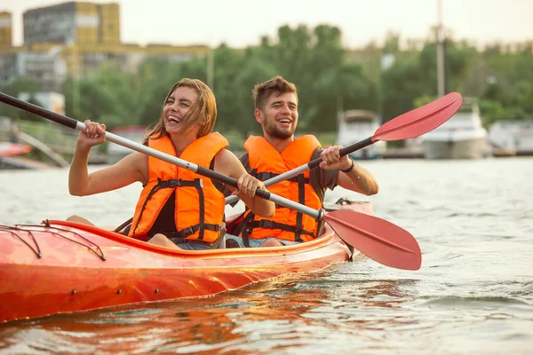 Happy couple kayaking on river with sunset on the background — Stock Photo, Image