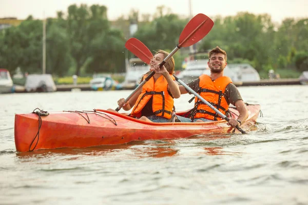 Glückliches Paar beim Kajakfahren auf dem Fluss mit Sonnenuntergang im Hintergrund — Stockfoto