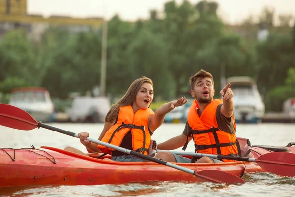 Happy couple kayaking on river with sunset on the background — Stock Photo, Image