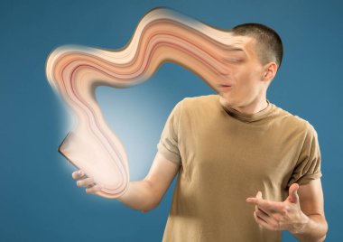 Alet ve sosyal medya ile meşgul olan genç adam mavi arka planda izole edilmiş.