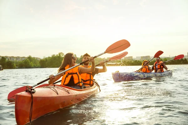 Happy friends kayaking on river with sunset on the background — Stock Photo, Image