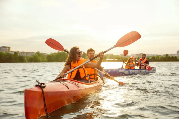 Heureux amis kayak sur la rivière avec coucher de soleil sur le fond — Photo