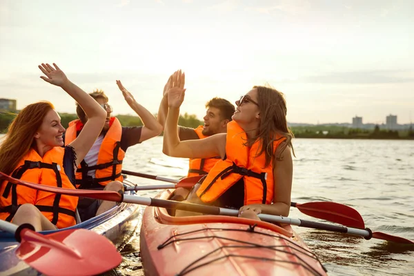 Felices amigos kayak en el río con puesta de sol en el fondo —  Fotos de Stock