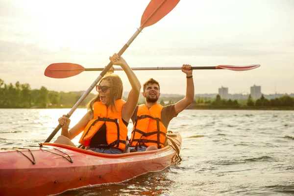 Happy couple kayaking on river with sunset on the background — Stock Photo, Image