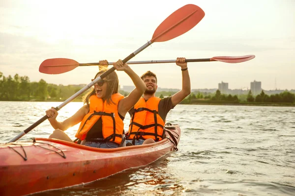 Pareja feliz kayak en el río con puesta de sol en el fondo —  Fotos de Stock