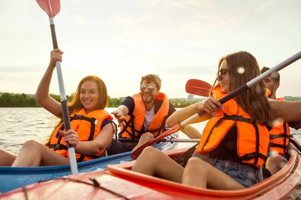 Happy friends kayaking on river with sunset on the background — Stock Photo, Image