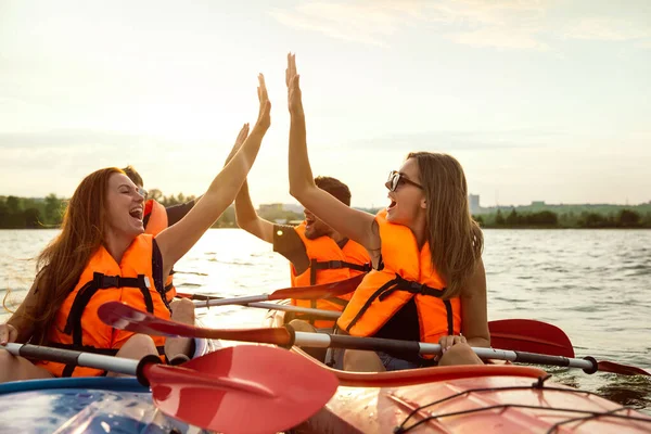 Glückliche Freunde Kajakfahren auf dem Fluss mit Sonnenuntergang im Hintergrund — Stockfoto