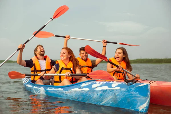 Lyckliga vänner kajakpaddling på floden med solnedgång på bakgrunden — Stockfoto