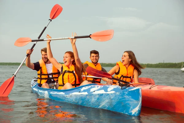 Glückliche Freunde Kajakfahren auf dem Fluss mit Sonnenuntergang im Hintergrund — Stockfoto