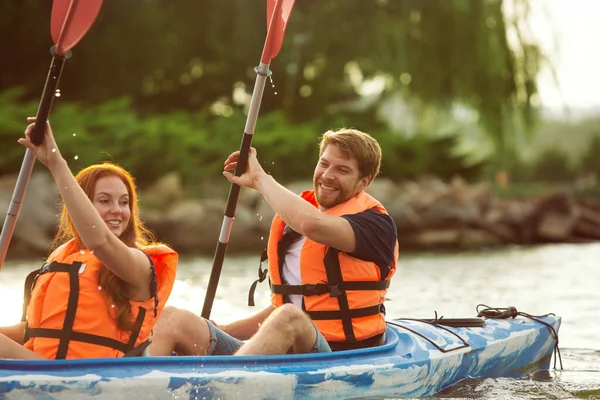 Happy couple kayaking on river with sunset on the background — Stock Photo, Image