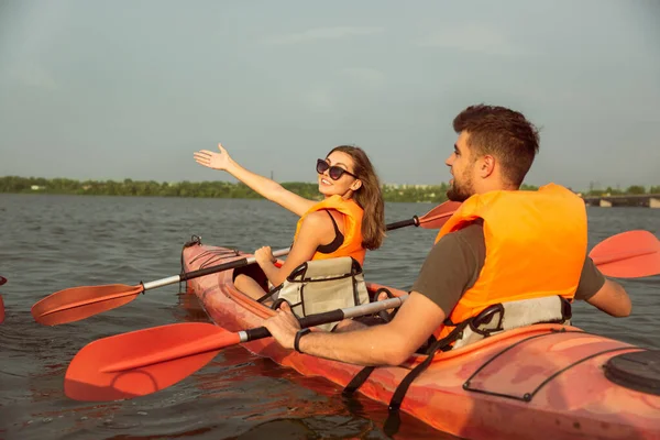 Glückliches Paar beim Kajakfahren auf dem Fluss mit Sonnenuntergang im Hintergrund — Stockfoto