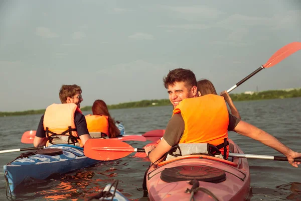 Happy friends kayaking on river with sunset on the background — Stock Photo, Image