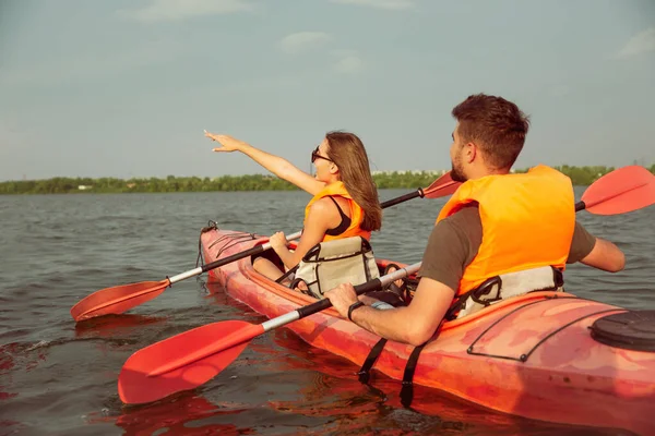 Coppia felice kayak sul fiume con tramonto sullo sfondo — Foto Stock