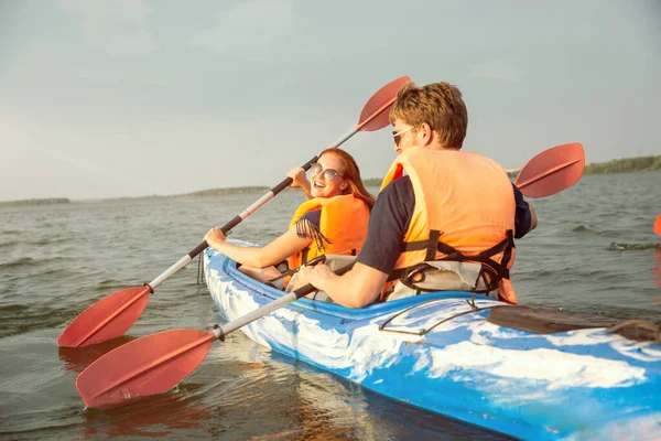 Happy couple kayaking on river with sunset on the background — Stock Photo, Image