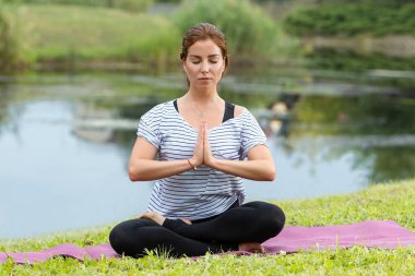 Genç ve güzel bir kadın Green Park 'ta yoga egzersizi yapıyor. Sağlıklı yaşam tarzı ve uygunluk kavramı.